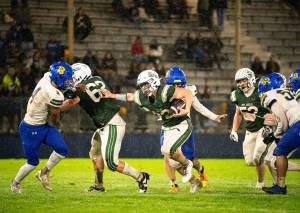 Port Angeles running back Dylan Mann (22) gets blocking from teammate Stryder Wilhelm (62) as he rushes for some of his 101 yards Friday night against Bremerton. The Knights won in extremely wet conditions 21-0. (Diamond Gentile/for Peninsula Daily News)