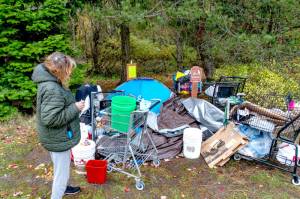 Janna Hall, 71, who said she lived at a homeless camp in Port Townsend for seven weeks, looks over her possessions that were to be moved by 5 p.m. Monday. Hall said she will be moving to an apartment in Portland today and she hopes to work part-time as a caregiver. (Steve Mullensky/for Peninsula Daily News)