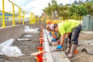 Workers from Van Ness Construction of Port Hadlock smooth out newly poured curbs and gutters on Tuesday as part of the Port of Port Townsends stormwater recovery system, an ongoing project at the Port Townsend Marina. (Steve Mullensky/for Peninsula Daily News)