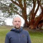 Erik Kingfisher near a large Madrona at Fort Worden State Park on Tuesday after receiving the Eleanor Stopps Environmental Leadership Award. (Elijah Sussman/Peninsula Daily News)