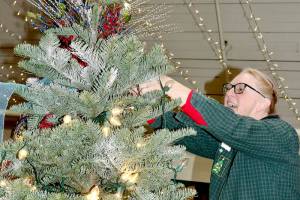 Sherilyn Seyler puts the lights on her tree for the Festival of Trees on Monday. Her tree is named Christmas at the Hucklebeary Ranch. There will be 45 trees and a variety of wreaths, all created by some of the Peninsulas best designers, some of whom have decorated trees for all 35 years of the Olympic Medical Center Foundation event. Opening ceremonies will begin today at 5 p.m. at the Vern Burton Community Center, 308 E. Fourth St., Port Angeles. (Dave Logan/for Peninsula Daily News)