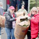 Donna Bower, left, and Kristine Konapaski, volunteers from the Michael Trebert Chapter of the Daughters of the American Revolution, unload one of the 115 boxes of Christmas wreaths and carry it to a waiting truck. (Dave Logan/For Peninsula Daily News)