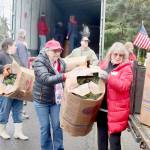 Donna Bower, left, and Kristine Konapaski, volunteers from the Michael Trebert Chapter of the Daughters of the American Revolution, unload one of the 115 boxes of Christmas wreaths and carry it to a waiting truck. (Dave Logan/For Peninsula Daily News)