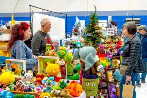 Pamela and Ernie Burnett, left, talk about their craft items, Amijurmi  Japanese small crocheted stuffed yarn creatures  to Tracey Harris of Marrowstone Island on Saturday during the first of two days at the 38th annual Chimacum Arts and Crafts Show at Chimacum High School. (Steve Mullensky/for Peninsula Daily News)