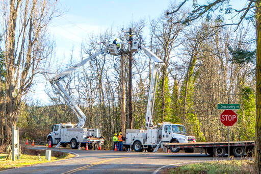 A crew from the Mason County PUD, in support of the Jefferson County PUD, works to replace a power pole and reconnect the power lines after a tree fell onto the wires and damaged the pole at the corner of Discovery Road and Cape George Road, near the Discovery Bay Golf Course. Powerful winds on Tuesday and early Wednesday morning knocked out power across the Peninsula. The majority had been restored by Wednesday. (Steve Mullensky/for Peninsula Daily News)