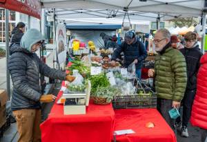 Joe McDonald, from Fort Worth, Texas, purchases a bag of Brussels sprouts from Red Dog Farm on Saturday, the last day of the Port Townsend Farmers Market in Uptown Port Townsend. The market will resume operations on the first Saturday in April 2026. (Steve Mullensky/for Peninsula Daily News)