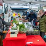 Joe McDonald of Fort Worth, Texas, purchases a bag of Brussels sprouts from Red Dog Farm on Saturday, the last day of the Port Townsend Farmers Market in Uptown Port Townsend. The market will resume operations on the first Saturday in April. (Steve Mullensky/for Peninsula Daily News)