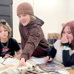 Stevens Middle School eighth-grader Linda Venuti, left, and seventh-graders Noah Larsen and Airabella Rogers pour through the contents of a time capsule found in August by electrical contractors working on the new school scheduled to open in 2028. The time capsule was buried by sixth graders in 1989. (Paula Hunt/Peninsula Daily News)