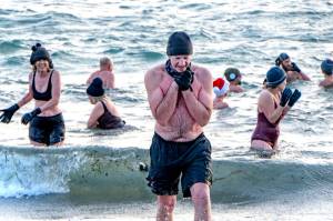Tom Malone of Port Townsend, seeks the warmth of a towel and a shirt as he leaves the 46-degree waters of the Salish Sea on Saturday after he took a cold plunge to celebrate the winter solstice. You cant feel the same after doing this as you did before, Malone said. (Steve Mullensky/for Peninsula Daily News)