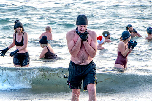 Tom Malone of Port Townsend, seeks the warmth of a towel and a shirt as he leaves the 46-degree waters of the Salish Sea on Saturday after he took a cold plunge to celebrate the winter solstice. You cant feel the same after doing this as you did before, Malone said. (Steve Mullensky/for Peninsula Daily News)