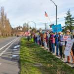 Members of Port Townsend Indivisible, a political protest group, begin to amass along Sims Way on Saturday in the first rally of 2026. The group was called to action in protest of the U.S. government and Donald Trump ousting the president of Venezuela overnight. Gina McMather, second from the right, a member of the Indivisible leadership team, led the pop-up rally. (Steve Mullensky/for Peninsula Daily News)