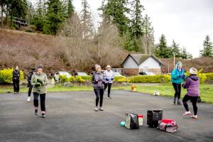 TJ Plastow, right, in purple coat, leads Lets Keep Moving, an outdoor fitness class at Port Ludlow Marina on Friday. The class participants are known to show up in all weather. On Friday, it was 40 degrees and breezy. (Steve Mullensky/for Peninsula Daily News)