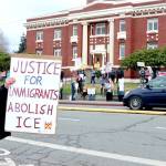 Miki White, left, is among about 100 demonstrators who filled both sides of Lincoln Street on Saturday in front of the Clallam County Courthouse in Port Angeles. Many held signs denouncing the U.S. Immigration and Customs Enforcement agency (ICE) after an agent shot and killed a Minnesota woman in her car last week. (Dave Logan/for Peninsula Daily News)