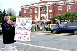 Miki White, left, is among about 100 demonstrators who filled both sides of Lincoln Street on Saturday in front of the Clallam County Courthouse in Port Angeles. Many held signs denouncing the U.S. Immigration and Customs Enforcement agency (ICE) after an agent shot and killed a Minnesota woman in her car last week. (Dave Logan/for Peninsula Daily News)
