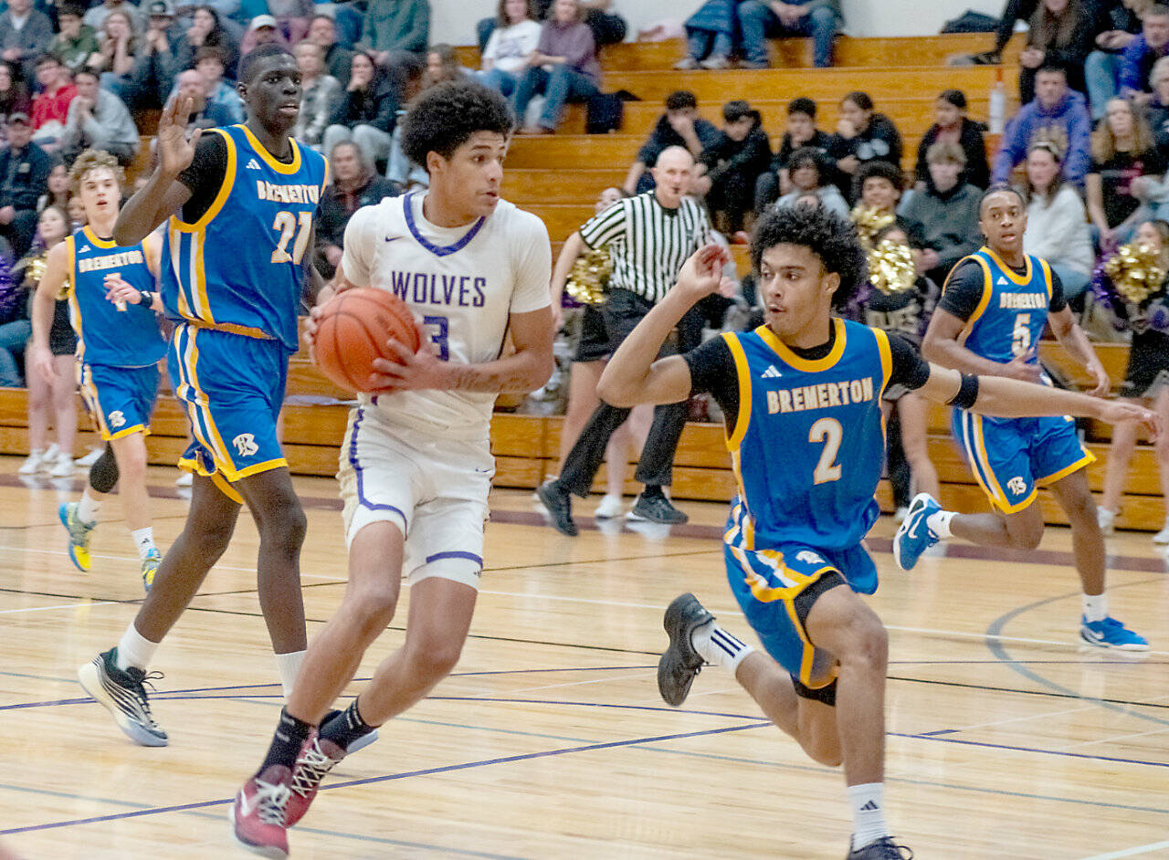 Sequims Solomon Sheppard drives the ball up the court against Bremertons Aaron Matthews. Sheppard led the Wolves with 21 points, but Sequim lost to the defending state champions 79-56. (Emily Mathiessen/for Peninsula Daily News)