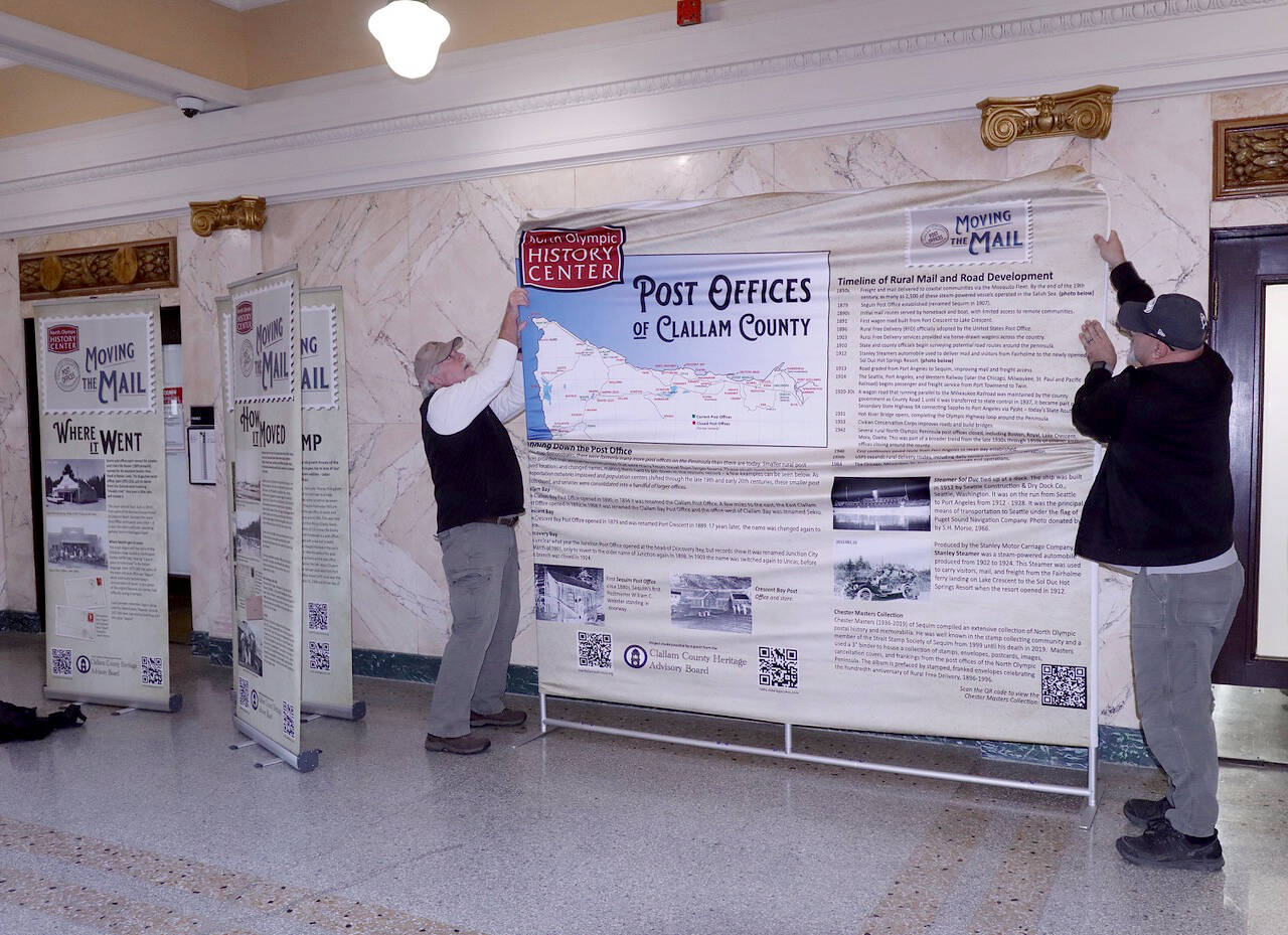 Bruce Murray, left, and Ralph Parsons hang a cloth exhibition in the rotunda of the old Clallam County Courthouse on Friday in Port Angeles. The North Olympic History Center exhibit tells the story of the post office past and present across Clallam County. The display will be open until early February, when it will be relocated to the Sequim City Hall followed by stops on the West End. The project was made possible due to a grant from the Clallam County Heritage Advisory Board. (Dave Logan/for Peninsula Daily News)