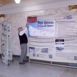 Bruce Murray, left, and Ralph Parsons hang a cloth exhibition in the rotunda of the old Clallam County Courthouse on Friday in Port Angeles. The North Olympic History Center exhibit tells the story of the post office past and present across Clallam County. The display will be open until early February, when it will be relocated to the Sequim City Hall followed by stops on the West End. The project was made possible due to a grant from the Clallam County Heritage Advisory Board. (Dave Logan/for Peninsula Daily News)