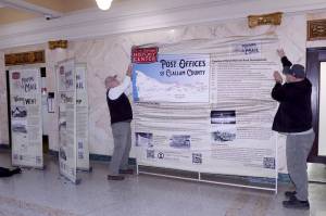 Bruce Murray, left, and Ralph Parsons hang a cloth exhibition in the rotunda of the old Clallam County Courthouse on Friday in Port Angeles. The North Olympic History Center exhibit tells the story of the post office past and present across Clallam County. The display will be open until early February, when it will be relocated to the Sequim City Hall followed by stops on the West End. The project was made possible due to a grant from the Clallam County Heritage Advisory Board. (Dave Logan/for Peninsula Daily News)