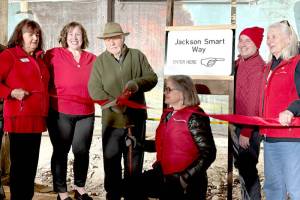 Jackson Smart, center with scissors, cuts the ribbon on Wednesday to officially open the newly remodeled section of the Port Angeles Underground Tour. With Smart are, from left, Julie Hatch, Kara Anderson, Elisa Simonsen, Sam Grello and Johnetta Bindas. (Laurel Hargis)