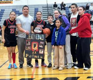 Neah Bay's Qwaapeys Greene and her family, including teammate and sister Diya Greene (20), celebrate her 1,000th point scored against Rainier on Saturday.