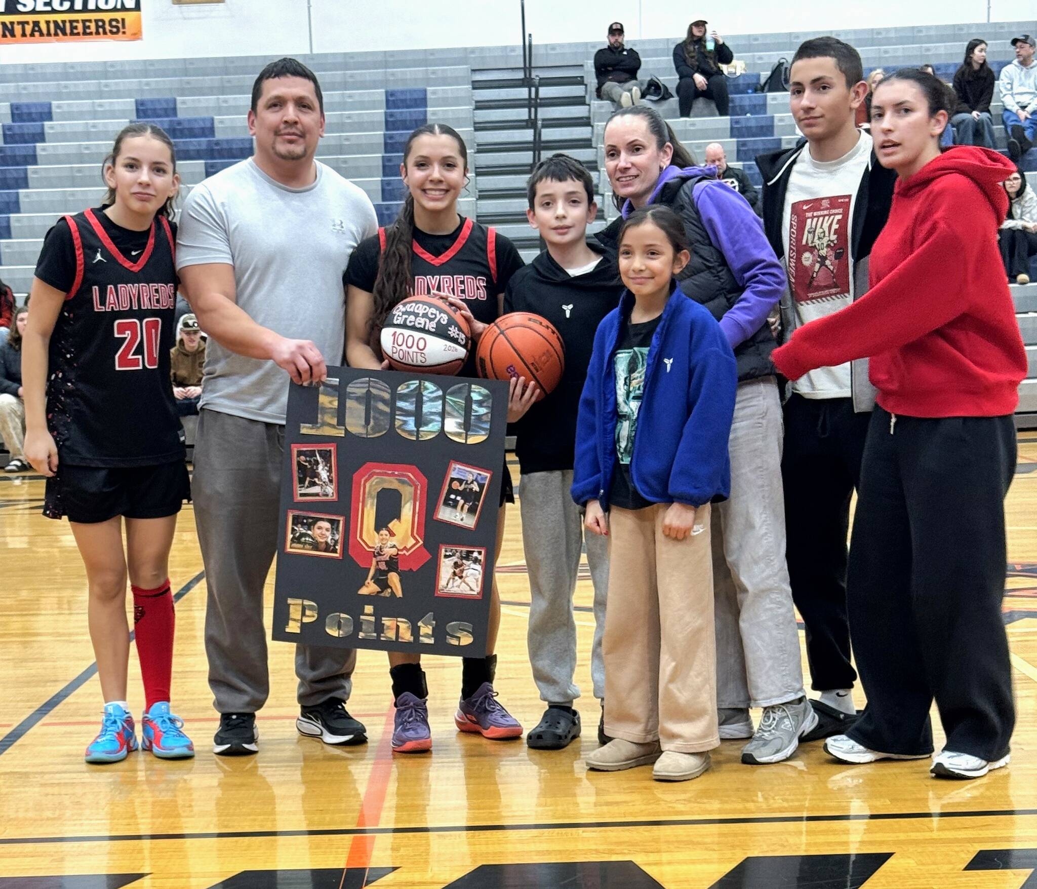 Neah Bays Qwaapeys Greene and her family, including teammate and sister Diya Greene (20), celebrate her 1,000th point scored against Rainier on Saturday.