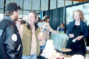Anthony DeLeon, left, and McKenzie Koljonen, who are planning a wedding in October, practice feeding each other a piece of wedding cake during the Olympic Peninsula Wedding Expo at Field Arts & Events Hall while Selena Veach of Aunt Selenas Bakery of Port Angeles watches with glee. More than 35 vendors presented all aspects of the wedding experience last weekend. (Dave Logan/for Peninsula Daily News)