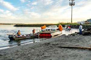Port of Port Townsend Harbormaster Kristian Ferrero, right, watches as a crew from Seattle Global Diving and Salvage work to remove a derelict catamaran that was stuck in the sand for weeks on a beach at the Water Front Inn on Washington Street in Port Townsend. The boat had been sunk off of Indian Point for weeks before a series of storms pushed it to this beach last week. (Steve Mullensky/for Peninsula Daily News)