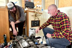 Northwest School of Wooden Boatbuilding Board President Richard Schwarz gets a rundown of the systems installed in a lobster boat built on campus by Iain Rainey, a recent graduate and current Marine Systems Prothero intern. (Northwest School of Wooden Boatbuilding)