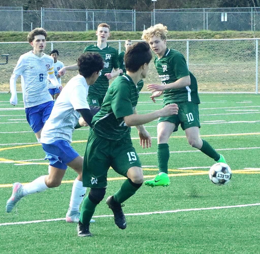 Port Angeles soccer player Matthew Miller (10) passes the ball forward to Roldan Lara (15) against Bremerton in Port Angeles on Saturday. Also in on the play is Port Angeles Sawyer Davis. The Roughriders came back from a two-goal deficit to win 3-2. (Dave Logan/for Peninsula Daily News)