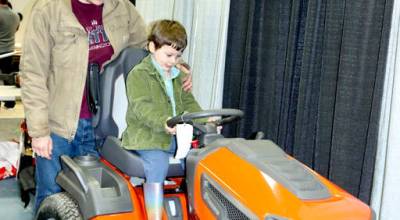 Bennett Smith-Ferguson, 4, tries out a riding lawn mower with his dad, Steve Smith, on Saturday during the 41st annual KONP Home Show at the Port Angeles High School gym. The two-day event featured exhibitors and presentations that showcased home improvement, landscaping and other services. (Dave Logan/for Peninsula Daily News)