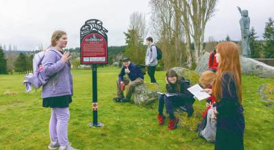 Maggie Parker, left, talks to her Blue Heron Middle School seventh-grade classmates about Chief Chetzemoka and his help in establishing Port Townsend as a settlement while on a field trip along the Chetzemoka Trail on Friday at Camas Prairie Golf Course. (Steve Mullensky/for Peninsula Daily News)