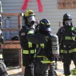 Firefighter/Paramedic Marquita Espinoza helps ready Firefighter/EMT Cole Smithson for a live fire training session inside the house at Gerhardt Park in Sequim. (Matthew Nash/Olympic Peninsula News Group)