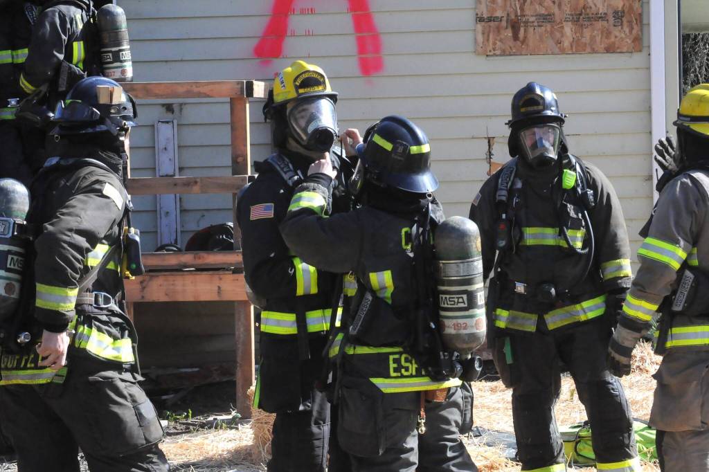 Firefighter/Paramedic Marquita Espinoza helps ready Firefighter/EMT Cole Smithson for a live fire training session inside the house at Gerhardt Park in Sequim. (Matthew Nash/Olympic Peninsula News Group)