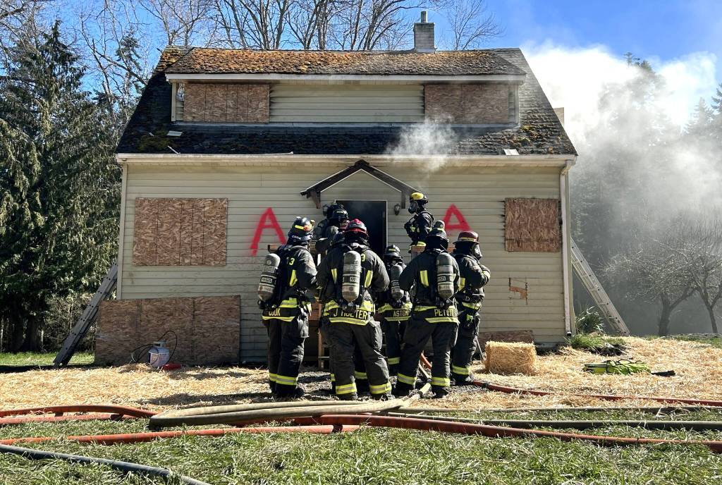 A group of Clallam County Fire District 3 firefighters prepare themselves before they go inside the ground floor of a live fire training on March 21. (Matthew Nash/Olympic Peninsula News Group)