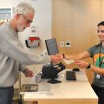Matthew Nash/Olympic Peninsula News Group
Richard Kaye of Sequim is the first patron to check out an item at the renovated Sequim Library. Hes helped by Amika Parr, a public service specialist. Kaye said he spotted the photography book America the Abandoned by Bryan Sansivero on the shelf as he walked in and checked it out within a few minutes of the library opening on March 21.