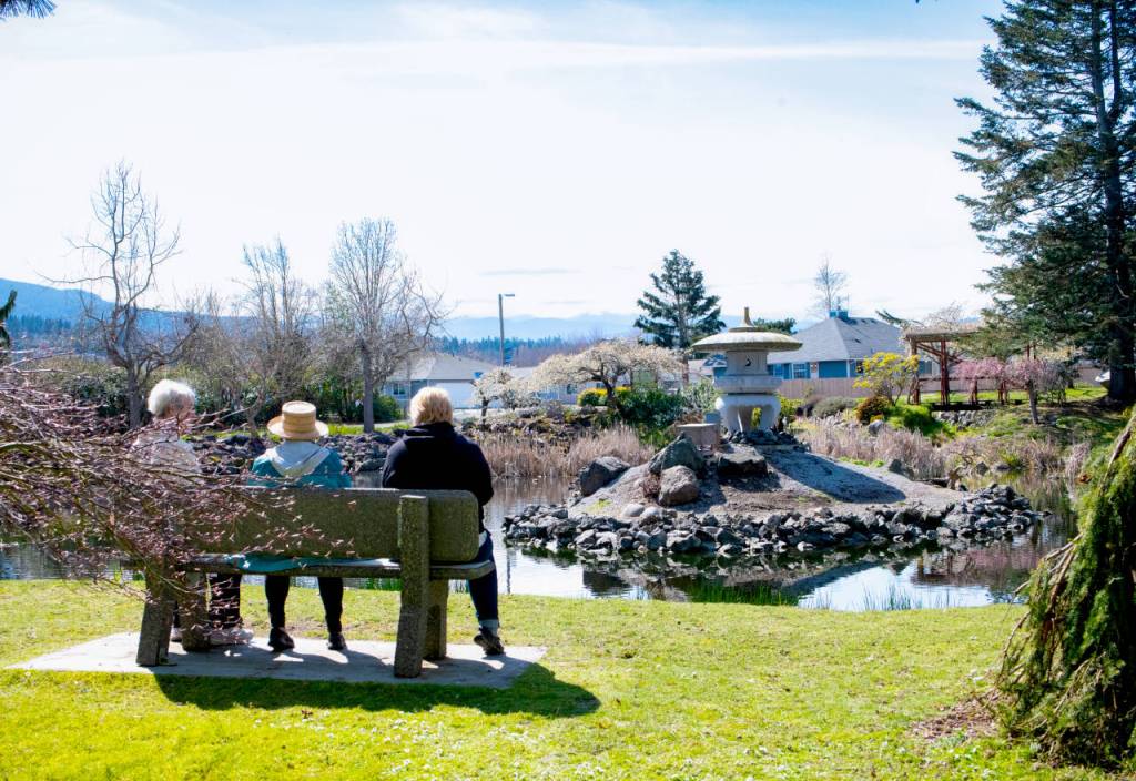 Visitors take in the view of the Friendship Gardens pond and the stone lantern that was delivered from Japan in fall 1997. (Monica Berkseth/Olympic Peninsula News Group)