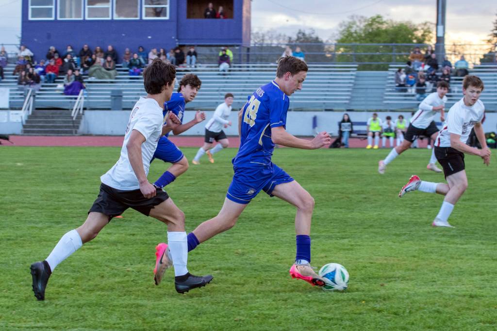 Emily Matthiessen/for Peninsula Daily News 
Sequim sophomore Colten Anderson bolts for the goal while being chased by Kingston defenders. Anderson earned and converted a penalty kick, the first of two penalty-kick goals for the striker in the Wolves 5-0 shutout of the Buccaneers on Thursday night.