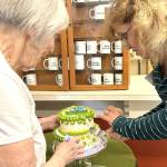 The Sunbonnet Sue Quilt Clubs most tenured member, Joanne Thoma, left, works with its newest, Stephannie Flynn, who joined two weeks ago, to cut a special cake made by the clubs youngest member, Sage Glover. Flynn said she moved to the area two years ago and wanted to be more active in the community and connected with the club through her neighbor Toni Cline. (Matthew Nash/Olympic Peninsula News Group)