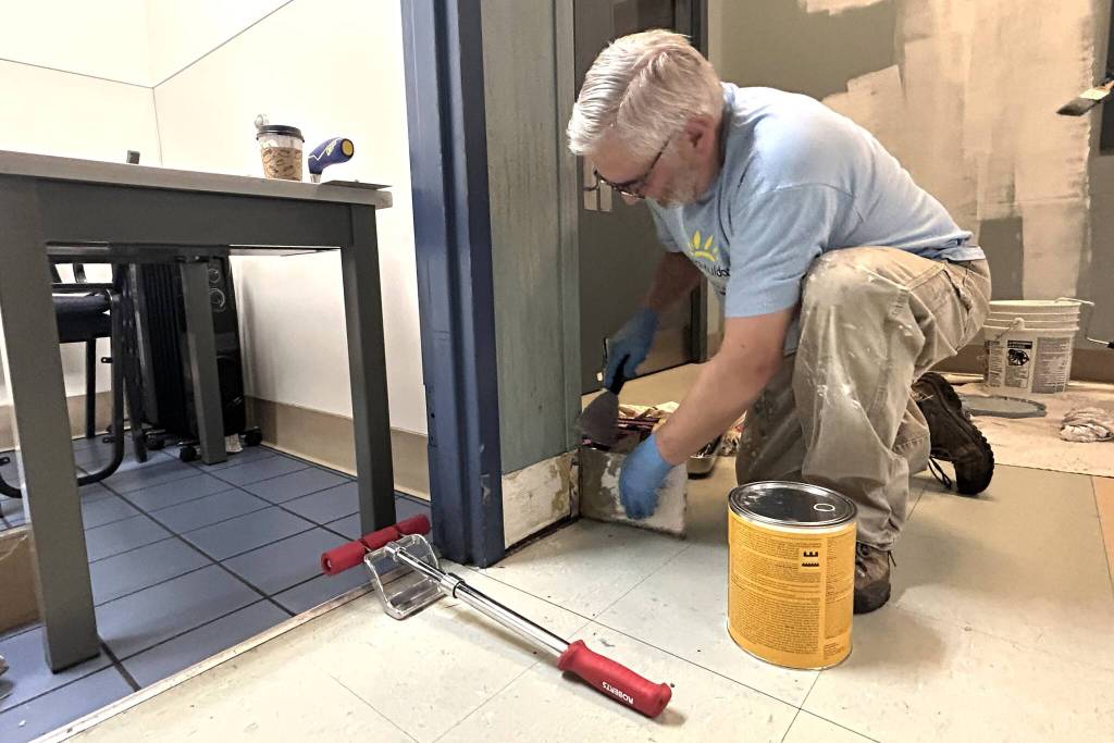 Tyler Conkle of Sequim Valley Foursquare works with fellow volunteers during Sequim Beautiful Day to paint and replace fiber reinforced polymer wall panels and cove base by the bathrooms inside the Sequim Boys & Girls Club. (Matthew Nash/Olympic Peninsula News Group)