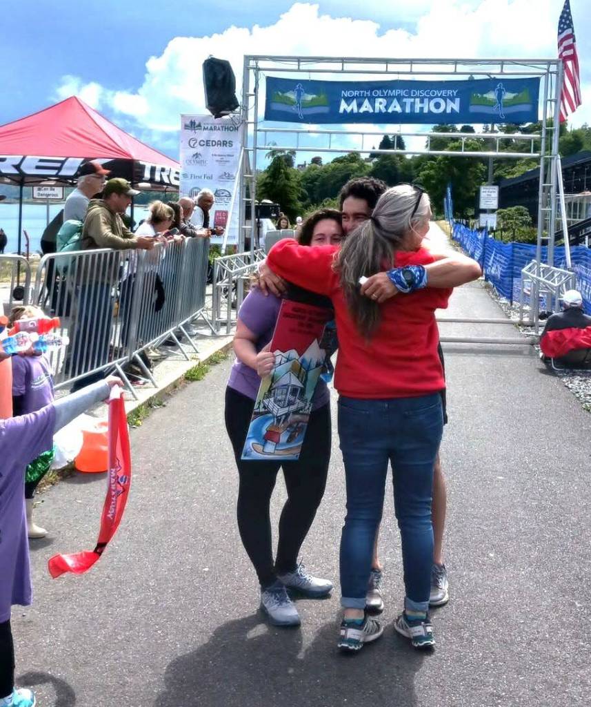 Michael Higuera gets a hug from NODM race officials after winning his first Run the Peninsula race. Higuera consistently finishes in the top five of every race he enters. (Pierre LaBossiere/Peninsula Daily News)