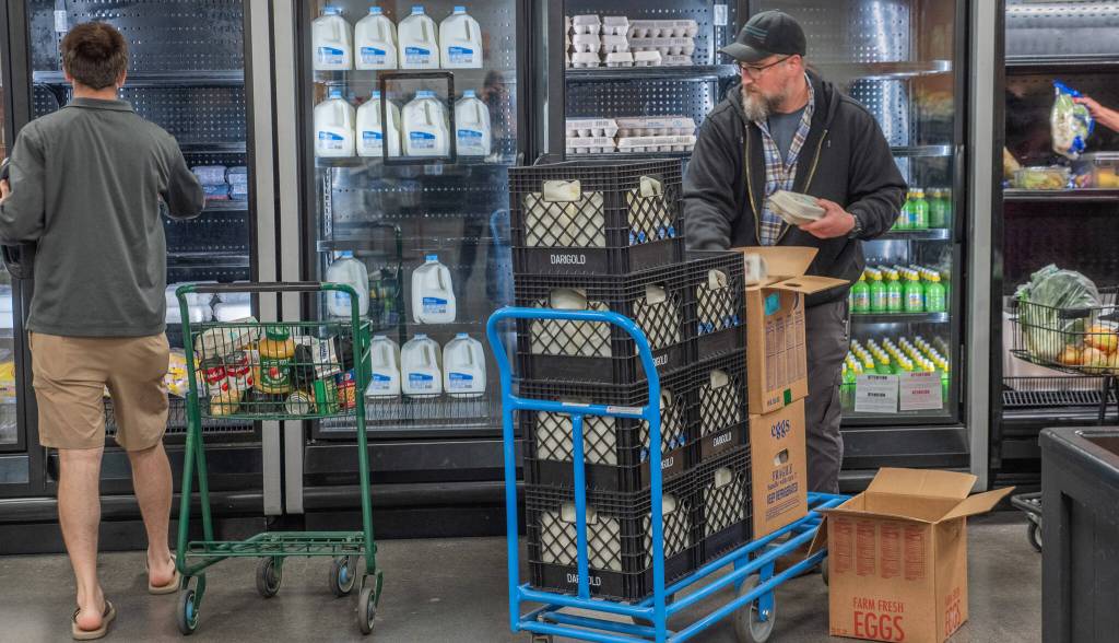 Emily Mathiessen / Olympic Peninsula News Group
A client shops at The Market at the Port Angeles Food Bank while Operations Manager Kevin Perry stocks the refrigerated cases.