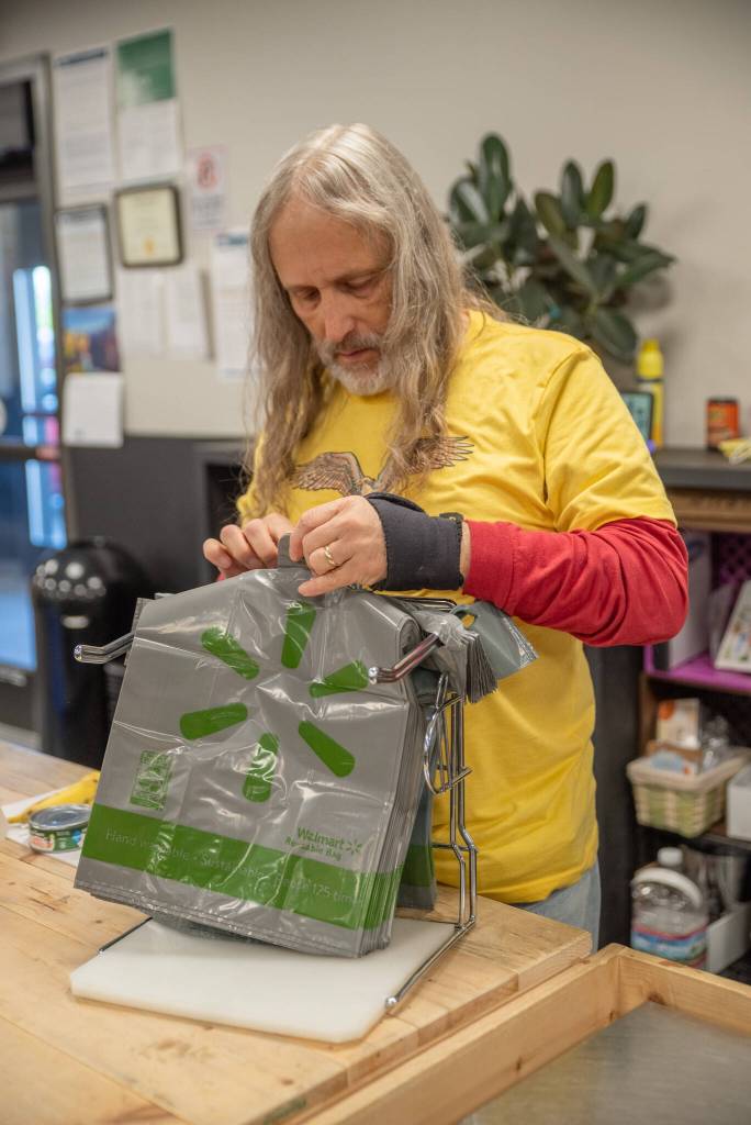 Volunteer Paul Stehr-Green prepares plastic bags for food bank clients. (Emily Mathiessen/Olympic Peninsula News Group)