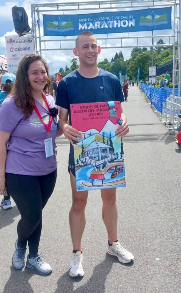 Jack Weaver of Bremerton won the mens 10K and is presented with his poster by Kaitlin Alderson. (Pierre LaBossiere/Peninsula Daily News)