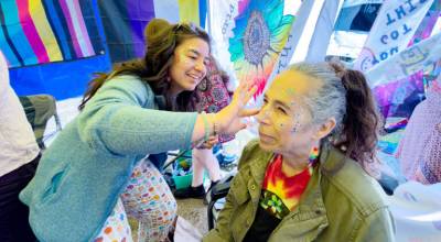Koyuke Fritchman of Port Townsend applies glitter to Rebecca Katz of Port Townsend during the Port Townsend Pride Festival on Saturday at Pope Marine Park. Fritchman is a teacher at Ocean Alternative School and volunteered her time and talents with glitter as a fundraiser for the LGBTQ+ club. An estimated 3,000 people attended the festival. (Steve Mullensky/for Peninsula Daily News)