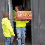 Kaysin Gluth passes fellow Sequim Food Bank youth volunteer Trinity McNorris as she carries a box of food from storage to an outdoor food station. (Emily Matthiessen/Olympic Peninsula News Group)
