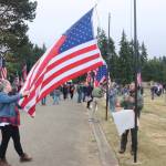 Volunteers Emily and Zach Batton of Sequim unfurl and raise one of the new 50 flags raised on Saturday at at the Mount Angeles Memorial Park Cemetery. More than a hundred people attended the special event, a project of the Carlsborg VFW and the Michael Trebert chapter of the Daughters of the American Revolution. (Dave Logan/for Peninsula Daily News)
