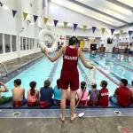 Savannah Minker, lifeguard and lead swim lesson instructor at the Y, demonstrates water rescue techniques to youth participating in Mini Lifeguard Camp. (Olympic Peninsula YMCA)
