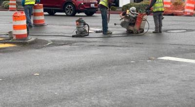 Bill Gyori, Tim Coville, Jeff Secord and Kevin Camacho of Interwest Construction Inc. make adjustments to a concrete saw at the intersection of First and Chambers streets in Port Angeles. The crew is performing pedestrian improvement work as part of the citys First and Front Pedestrian Enhancements project, which includes work on sidewalks, curbs and ramps, signage, striping and crosswalks. Work along First and Front streets is expected to continue through Aug. 17. (Kelley Lane/Peninsula Daily News)
