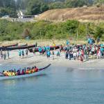 A canoe from the Scianew Tribe, from Beecher Bay on Vancouver Island, approaches the beach and asks permission to land from a Jamestown SKlallam tribal member on the beach during the 2024 event at Fort Worden in Port Townsend. Saturadys Canoe Journey landing may include up to 20 canoes and as many as 1,000 people. (Steve Mullensky/for Peninsula Daily News)