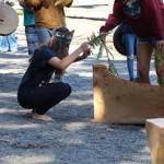 Valerie Charles blesses a canoe with a cedar branch dipped in Lake Crescent on Thursday at the NatureBridge Campus. (Emily Hanson/Peninsula Daily News)